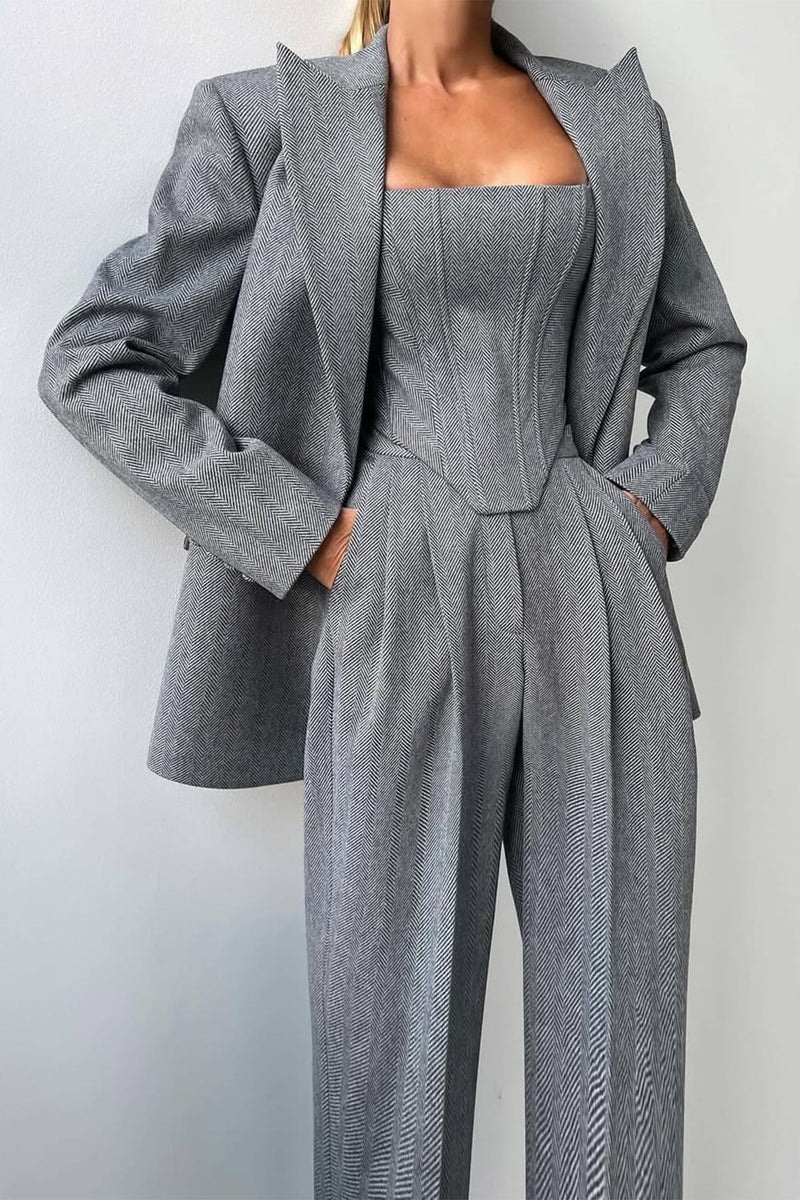 A woman wearing a double-breasted blazer with a matching top and trousers, all in a gray color.